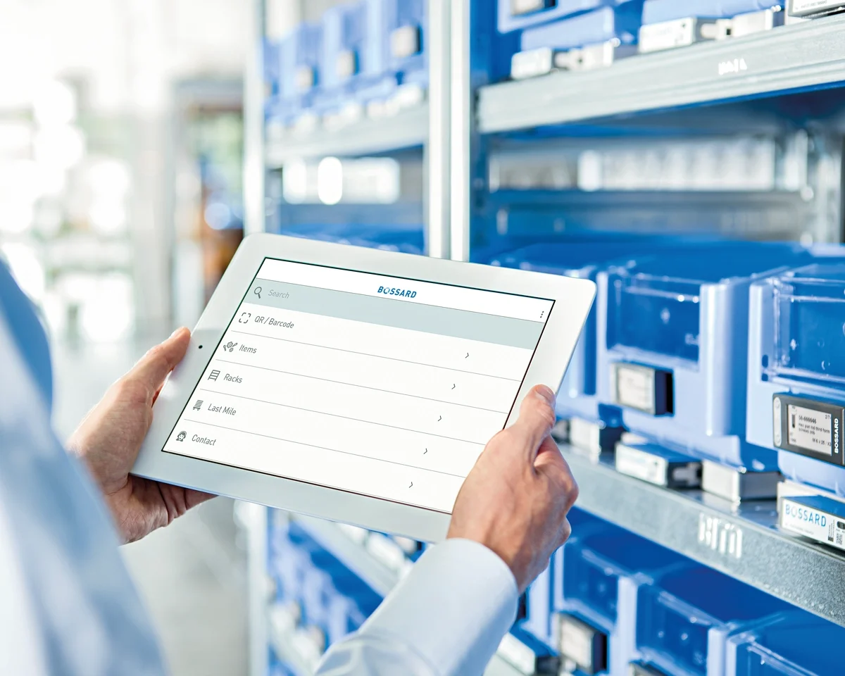 Person is checking stock information on a tablet in front of C-part bins