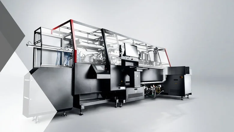 Large industrial machine with a sleek black and silver design, featuring a computer screen and red accents, on a gray background.
