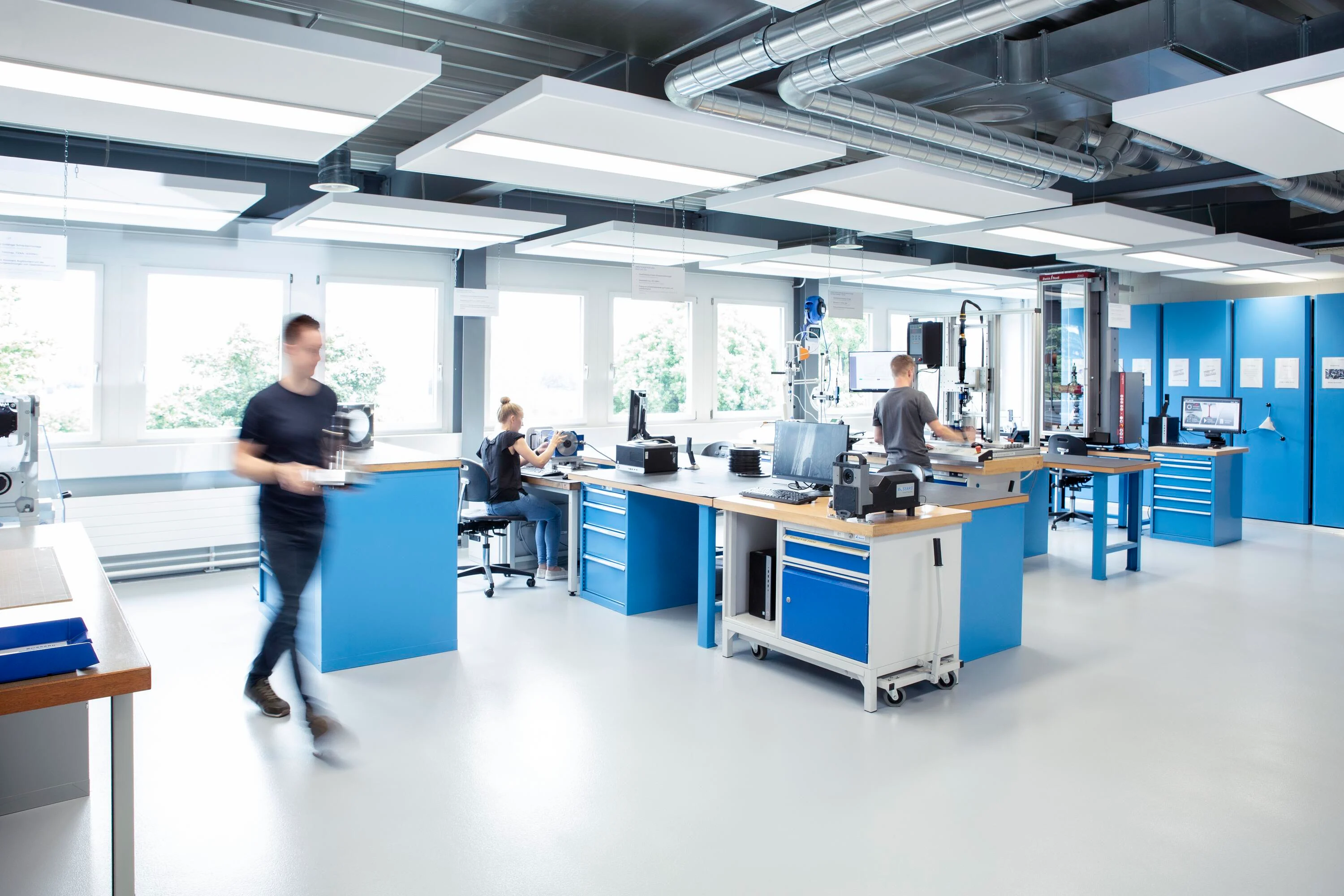 Three engineers collaborating on various tests in a well-equipped laboratory, with a clear view of both the team and the testing equipment.
